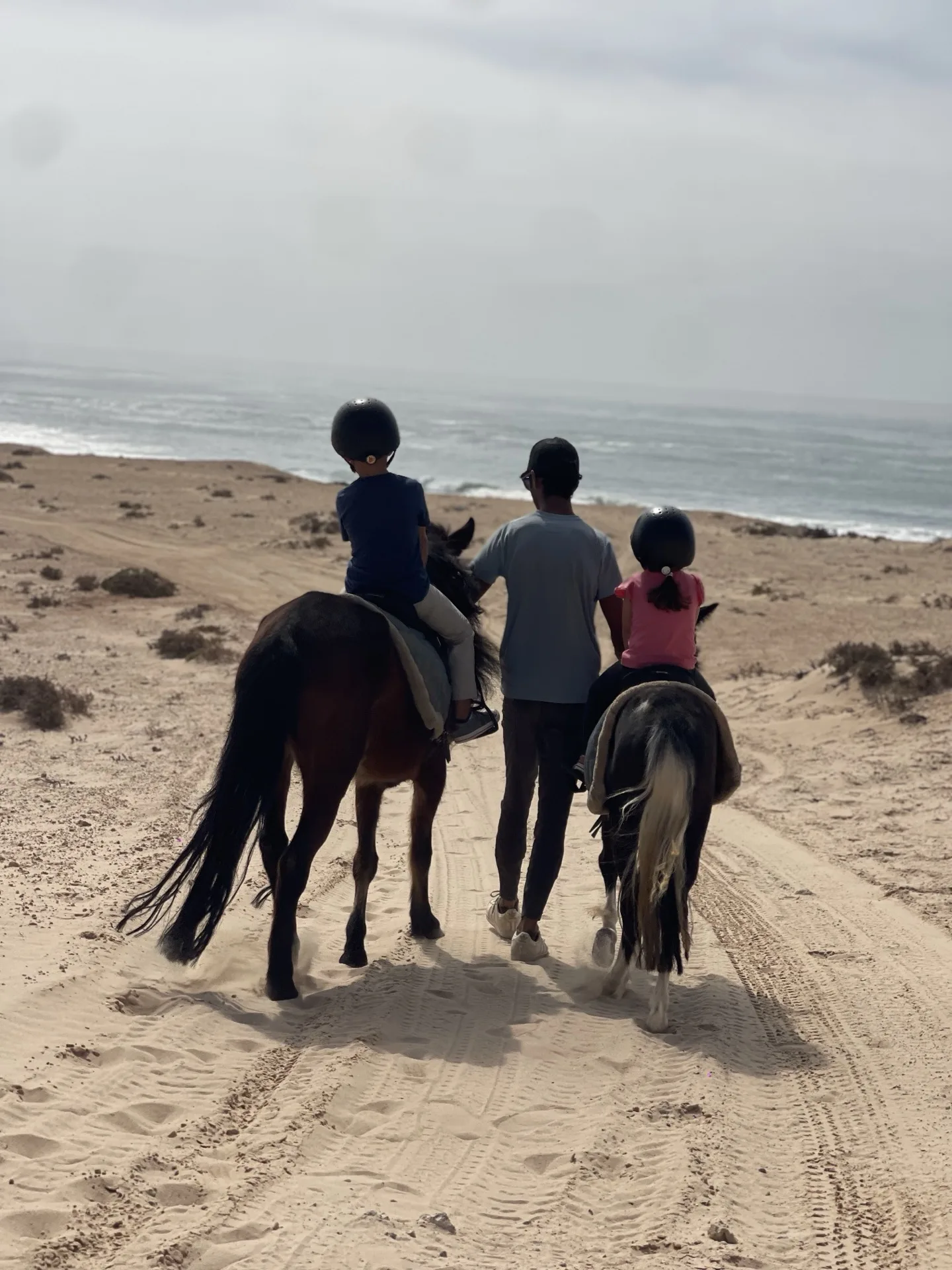 Enfant sur un poney guidé par un accompagnateur dans le désert de Dakhla