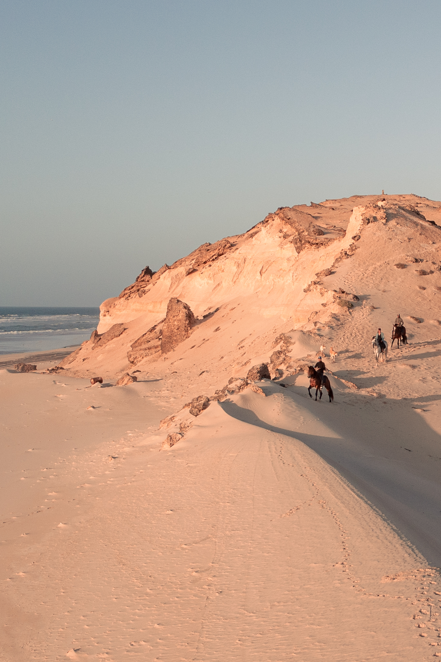 Vue drone de cavaliers longeant la plage entre les dunes et l'océan à Dakhla
