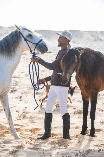 Salah préparant l'harnachement d'un cheval au Ranch des Dunes