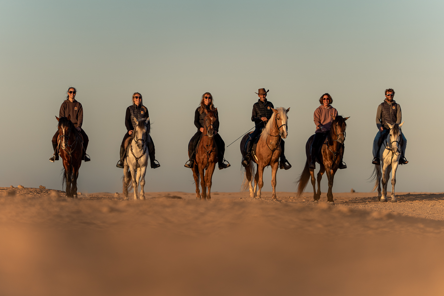 L'équipe du Ranch des Dunes à cheval dans les dunes de Dakhla au coucher du soleil