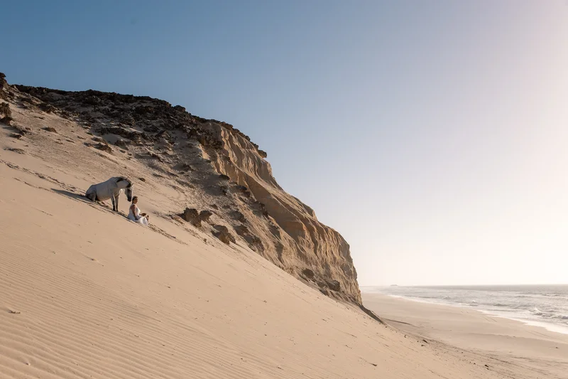Modèle avec cheval devant les falaises et l'océan à Dakhla